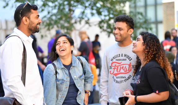 Four Kingston University students laughing outside on campus